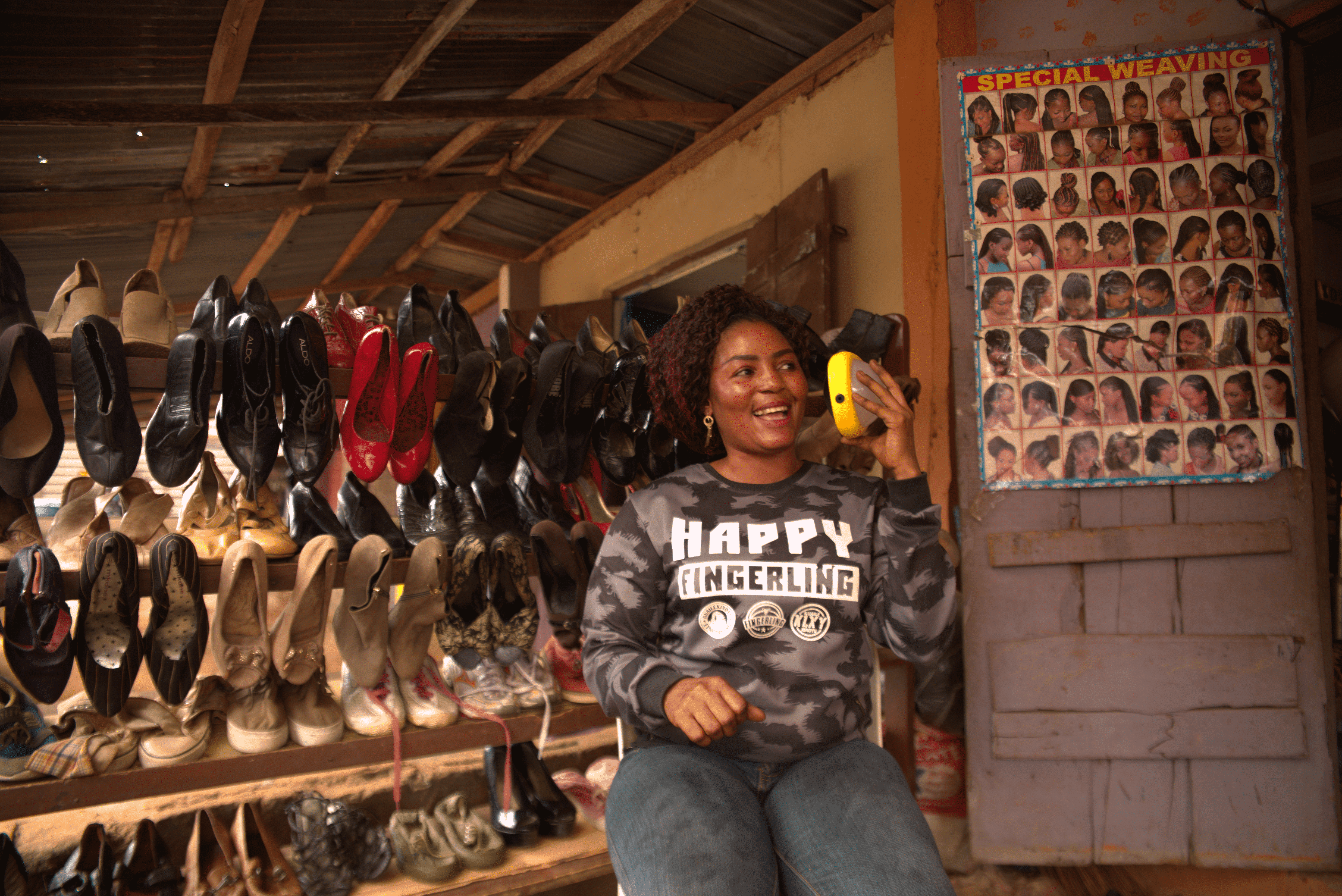Woman listening to her solar powered Sun King Boom outside her store.